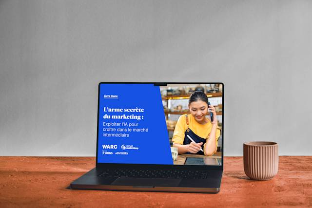 Ordinateur portable affichant le livre blanc « Le Grand Égaliseur du marketing » sur fond bleu, avec des bols en céramique sur une surface en bois.