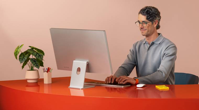 Man working on a computer on a bright red desk