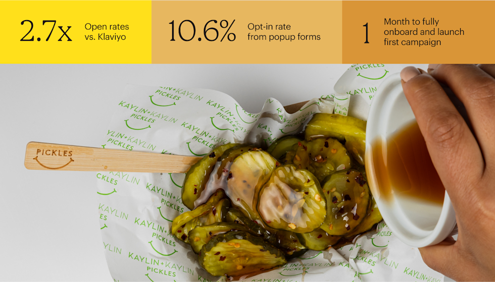 Pickle spears drizzled with white sauce on branded paper with green smiley face logo pattern and wooden fork